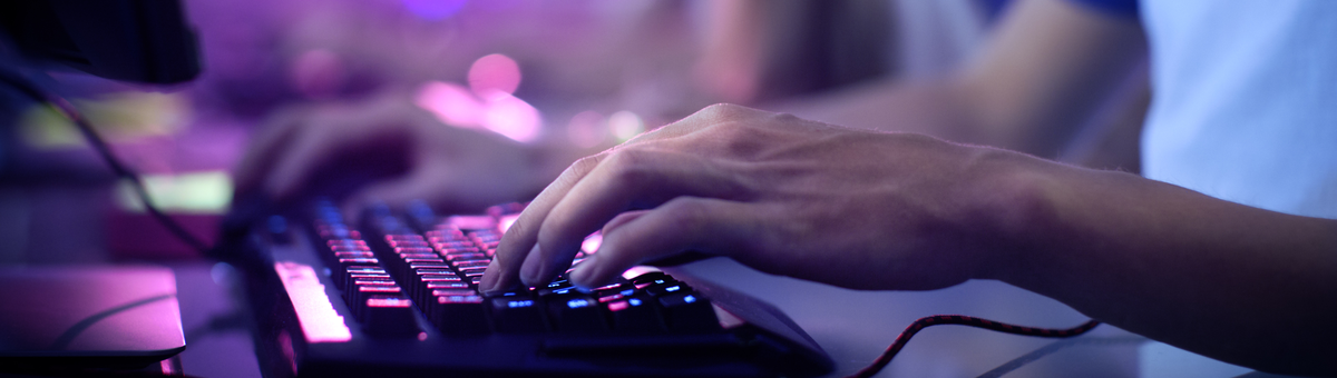 mees kasutab roosa taustvalgusega mänguri klaviatuuri
