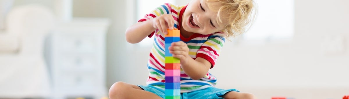 ребенок строит башню из кубиков