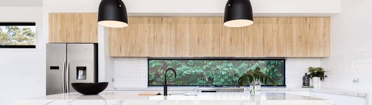 kaasaegne ja valgusküllane köök, kus ripuvad mustad valgustid köögisaare kohal